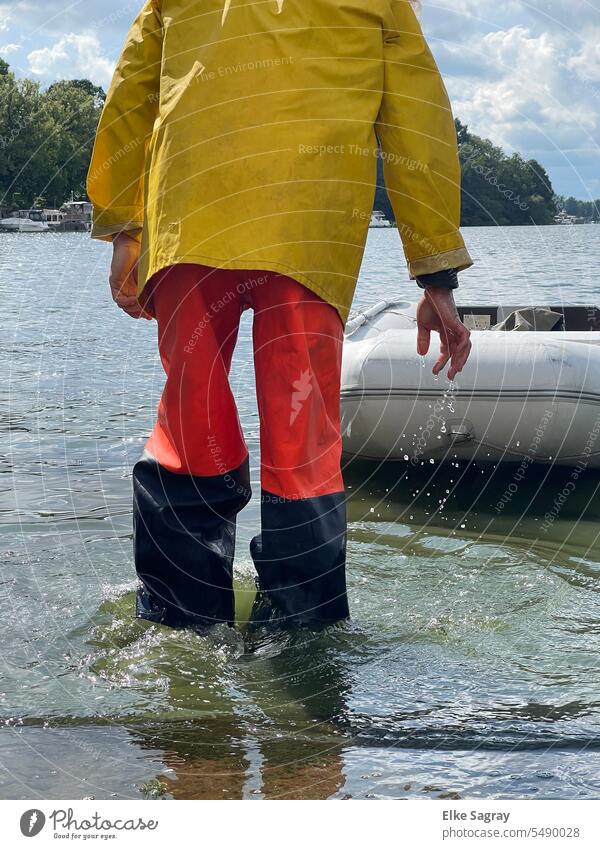 Man with rainwear in water Only one man Exterior shot Water Drops of water Surface of water Dinghy black red yellow Whirlpool Individual 1 Person Adults