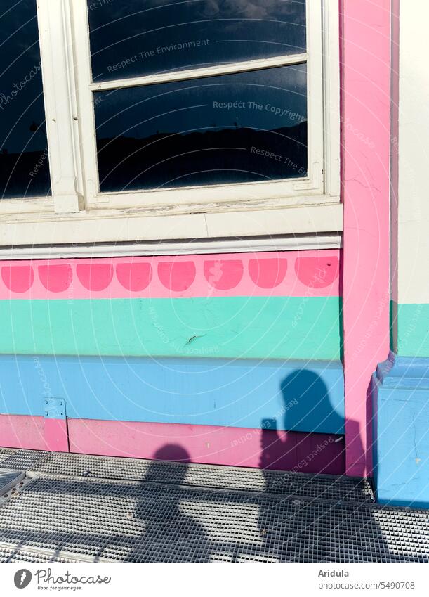 Shadow of two people on a colorful house facade with window, one person holds a cell phone in his hand persons outline shadow cast Silhouette