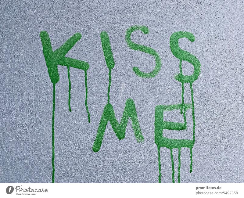 Kiss me.  Kiss me. Green lettering on a white wall. Photo: Alexander Hauk Kissing kiss kiss me green Art writing Letters (alphabet) Love Longing Exterior shot