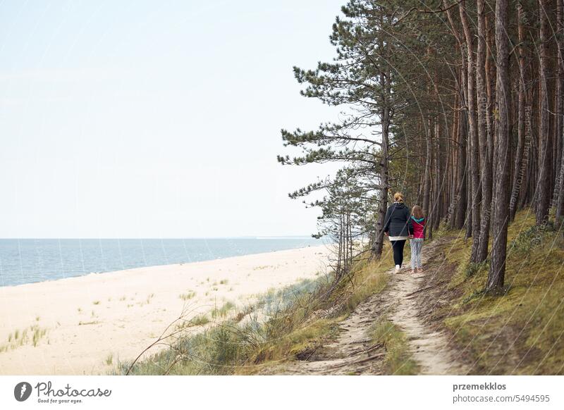 Woman and her daughter walking along seashore and forest. Family spending vacations at sea. Summer trip. Enjoying free time summer family beach person travel