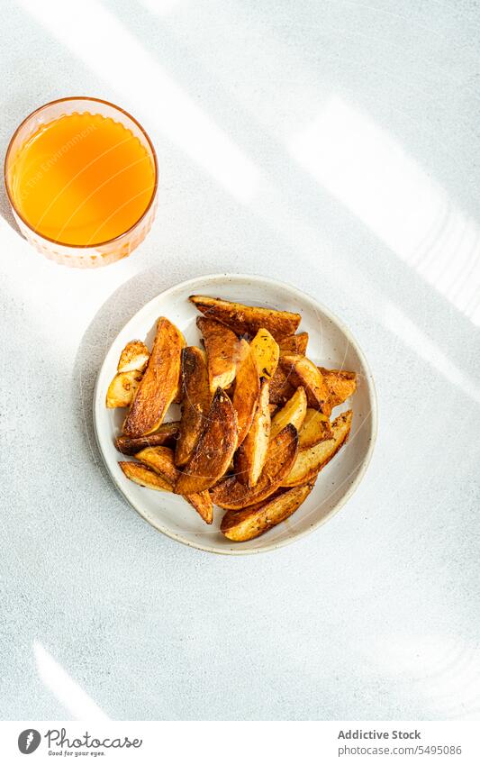 Fried potato with paprika spice served on ceramic plate near orange juice fried food drink glass table dish meal ingredient recipe yummy taste tasty eat dinner