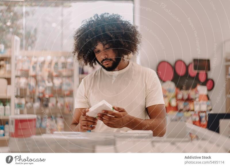 African American man with afro hair reading label on prescribed medicine at pharmacy buy information customer prescription drugstore lifestyle health care