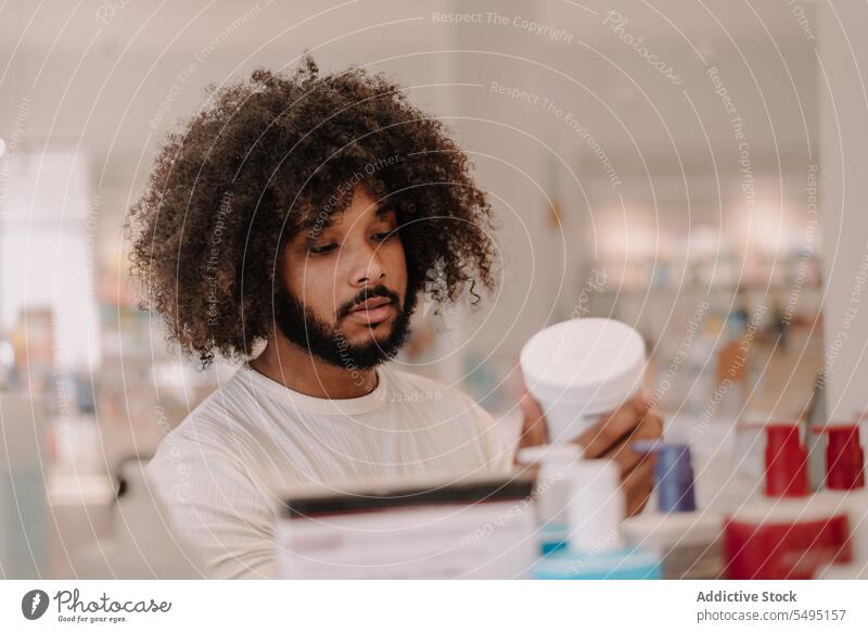Black man reading ingredient on drug bottle at pharmacy store drugstore label customer buy medicine prescription lifestyle beard health care package curly hair