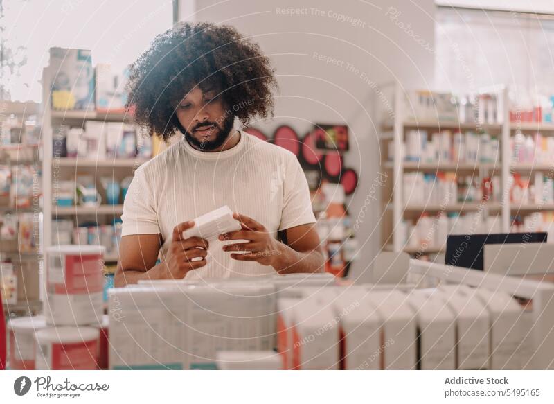 African American man with afro hair reading label on prescribed medicine at pharmacy buy information customer prescription drugstore lifestyle health care