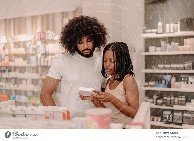 Black couple reading information on medicine package at drugstore boyfriend girlfriend pharmacy buy man woman health care shop purchase antibiotic client
