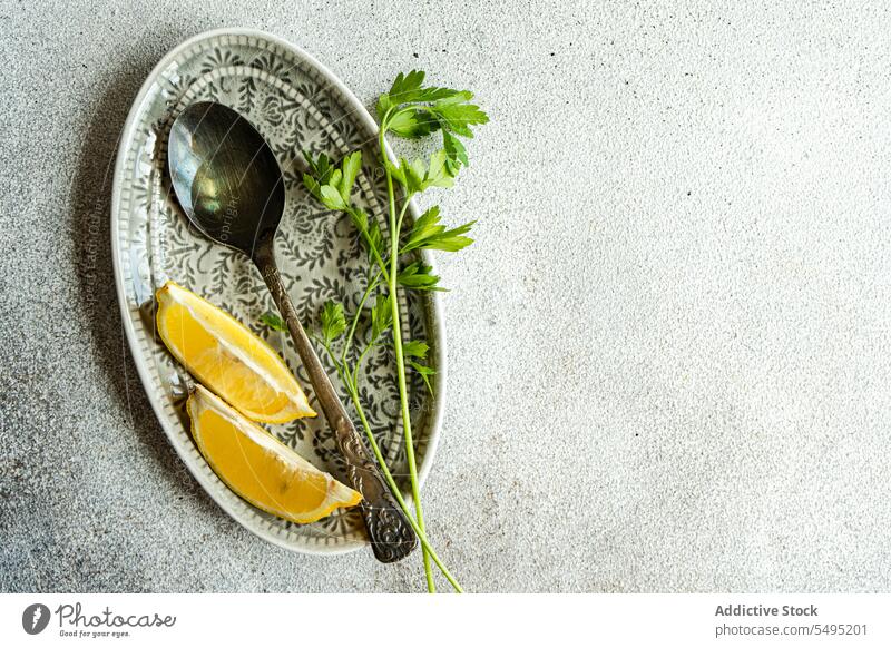 Spoon with virgin olive oil, lemon slices and green parsley herb on the plate spoon dish decorated colorful gray background high angle from above healthy