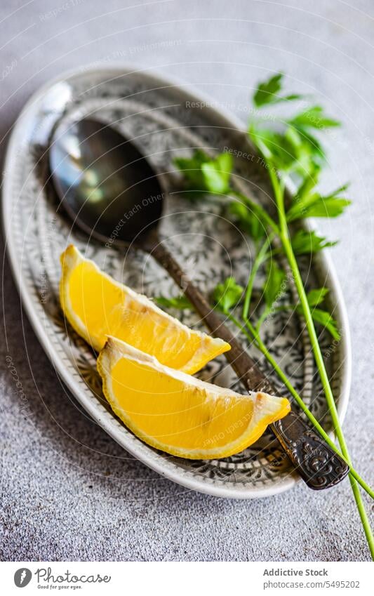 Spoon with virgin olive oil, lemon slices and green parsley herb on the plate spoon dish decorated blur blurred background colorful gray background high angle