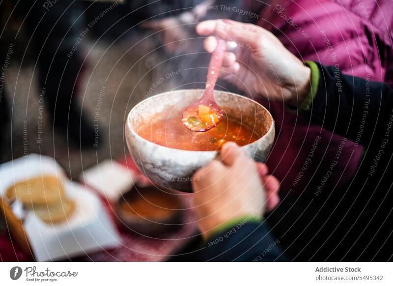 Unrecognizable man in black sweater holding steaming soup with spoon in hands person bowl table food dish vegetable male serve hot meal at home tasty fresh