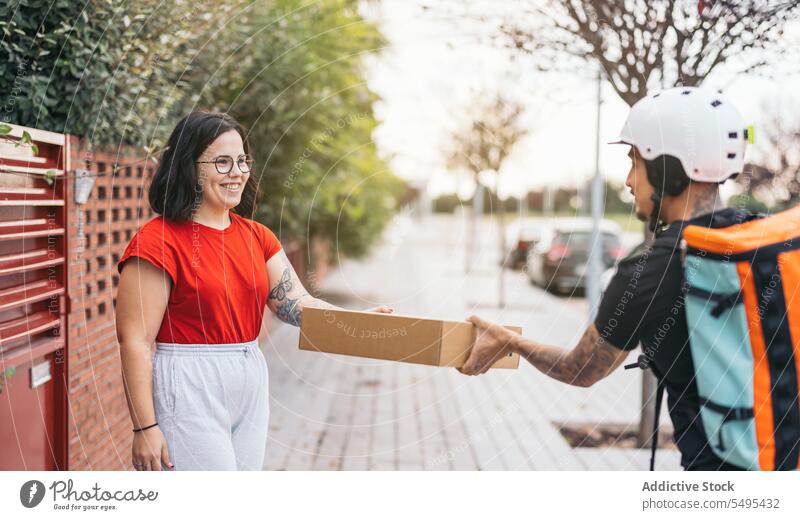 Happy customer receiving parcel from courier on sidewalk woman delivery man receive cardboard box smile package service protect safety shipping cheerful casual