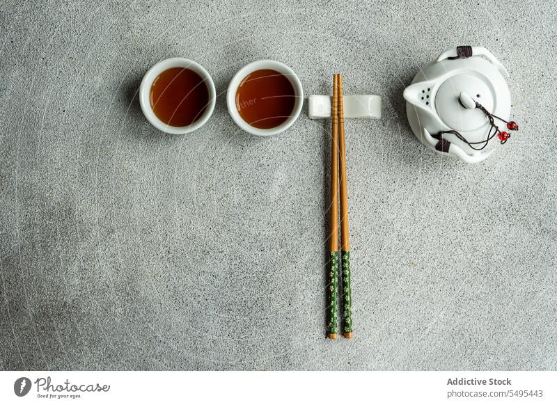 Tea set in Asian style with chopsticks as decoration tea asian table surface gray cup full drink beverage liquid jar ceramic green white brown isolated