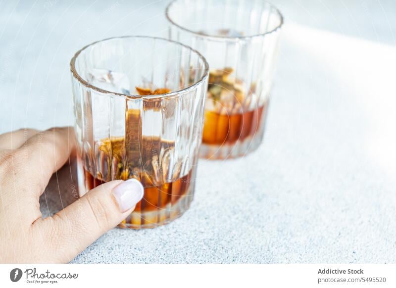 Anonymous person with glasses of whiskey with ice and orange peel container transparent crop blur blurred background fruit drink cool cold beverage alcohol