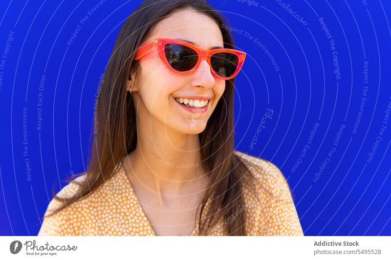Smiling woman in sunglasses against blue background smile trendy style bright positive happy cheerful leisure young outfit modern appearance female eyewear joy