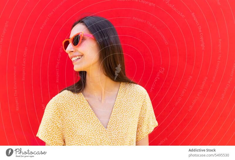 Smiling woman in sunglasses against red background smile trendy style bright positive happy cheerful leisure young outfit modern appearance female eyewear joy