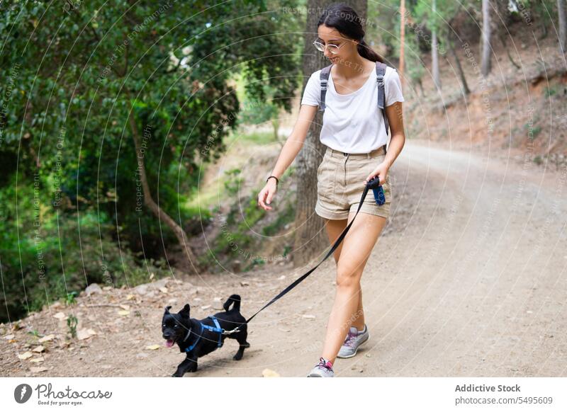 Full body of positive girl with dog woman owner black dog glad domestic puppy breed carefree pet female canine animal pedigree stroll together smile walk lady