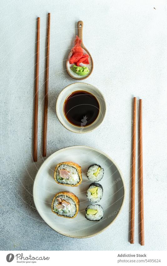 Top view of japanese food placed on a white concrete table serve set sushi roll bowl salmon rice seaweed soy sauce asian food chopstick healthy cookery culinary