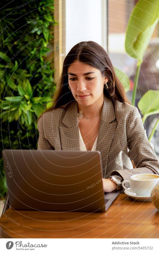 Woman sitting at table with coffee cup and working on laptop woman freelance remote internet startup workplace cafe female online browsing surfing gadget device