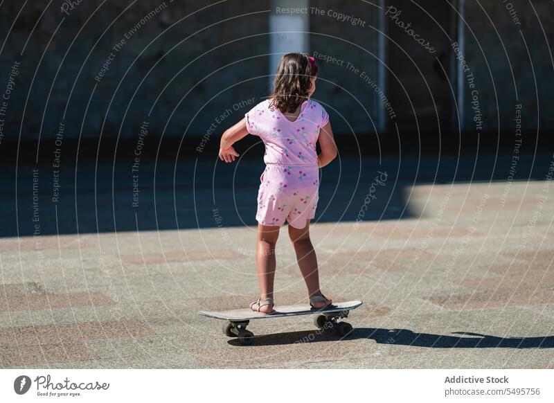 Little girl riding longboard on sunny street ride skater child city kid summer activity hobby casual lifestyle cute pavement childhood little motion energy cool