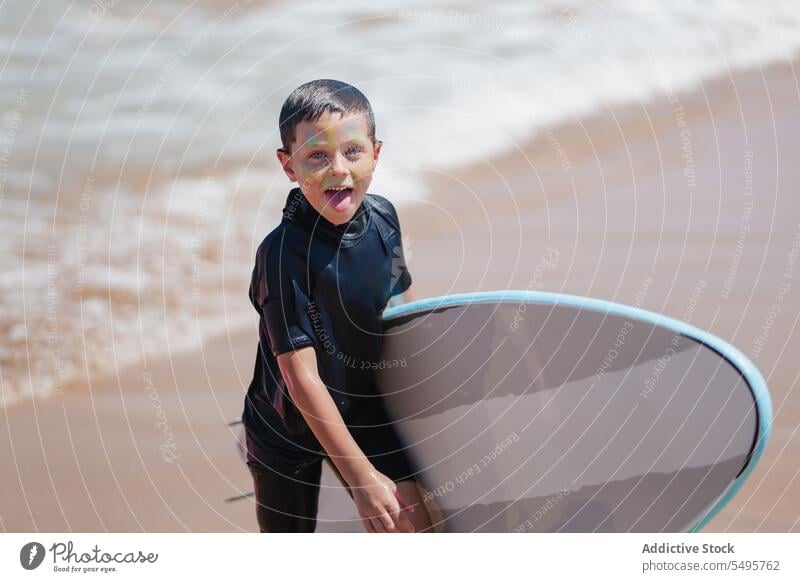 Cheerful boy with surfboard on sandy beach summer walk sea carry surfer smile kid happy positive joy child funny vacation activity childhood summertime holiday