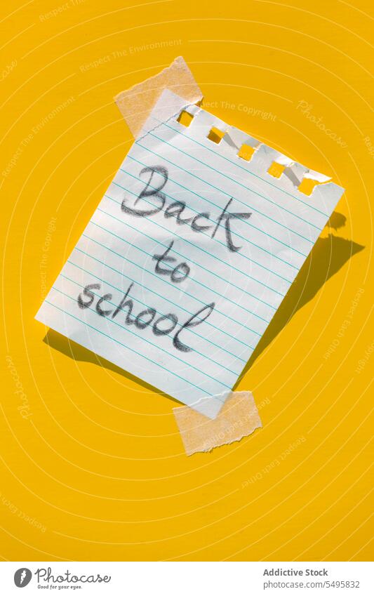 Note with message back to school pasted on yellow wall stationery reminder write notebook page line sticker background spiral modern design creative memo paper