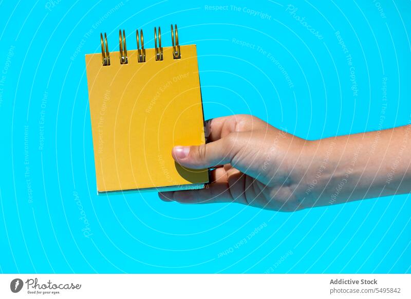 Crop hand with spiral notebook in blue studio notepad bright blank mockup hold show demonstrate concept vibrant education paper diary color study vivid creative