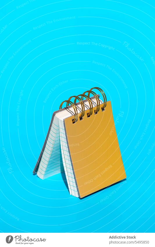 Yellow hardcover spiral bound notebook on blue backdrop bind page paper line information floor notepad memo creative minimal composition sheet stationery bright