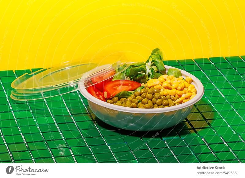 Salad bowl on green background with plastic cover against yellow wall salad food slice tomato spinach leaf corn kernel pea colorful surface table healthy eat