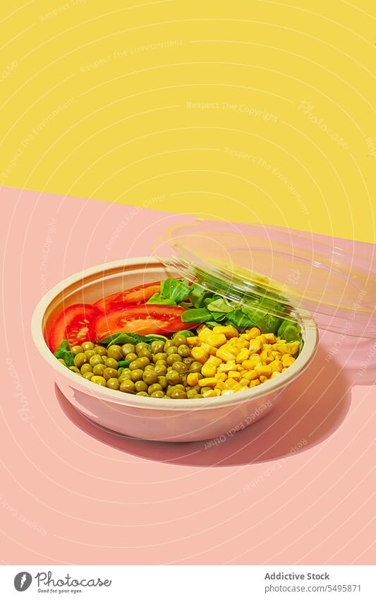 Salad bowl on pink background with plastic cover salad food slice tomato spinach leaf corn kernel pea colorful surface table healthy eat yummy fresh meal