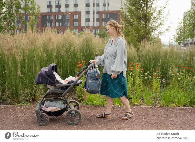 Woman pushing baby in stroller while walking in park mother plant woman family infant buggy backpack lifestyle green pushchair love together care affection