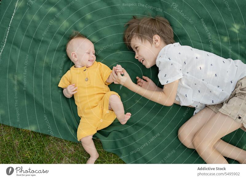 Cute brother with baby sibling lying on blanket in park boy cute resting weekend together smile children lifestyle cheerful love childhood adorable little