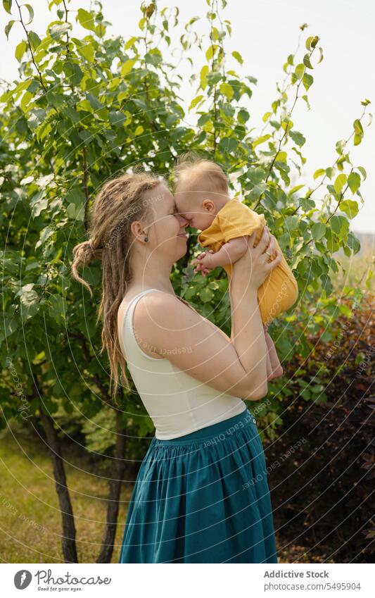 Loving woman carrying baby while standing in park mother love summer weekend family infant together motherhood care hipster affection nature happy eltern