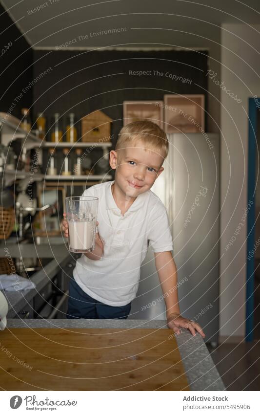 Smiling boy holding milk glass and standing in kitchen glasse cook cute smiling food countertop drink healthy blonde hair smile lifestyle looking house