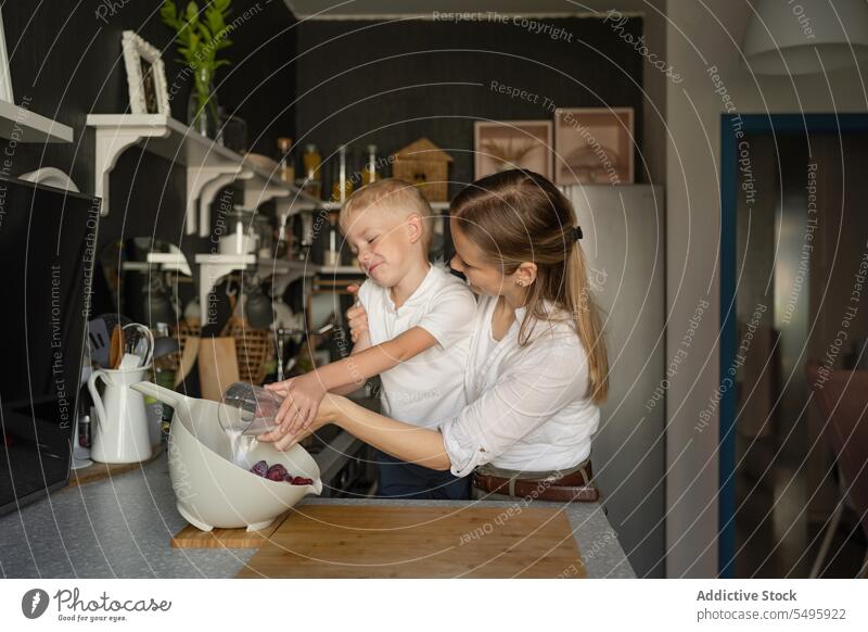 Woman and boy pouring milk in bowl in kitchen mother son strawberry cooking woman family fruit glasses smile love childhood holding together free time cute