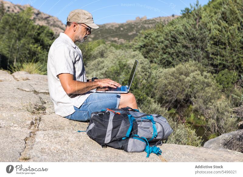 Man using laptop on rocky cliff man freelance work nature browsing traveler male plant remote gadget summer device internet surfing computer online connection