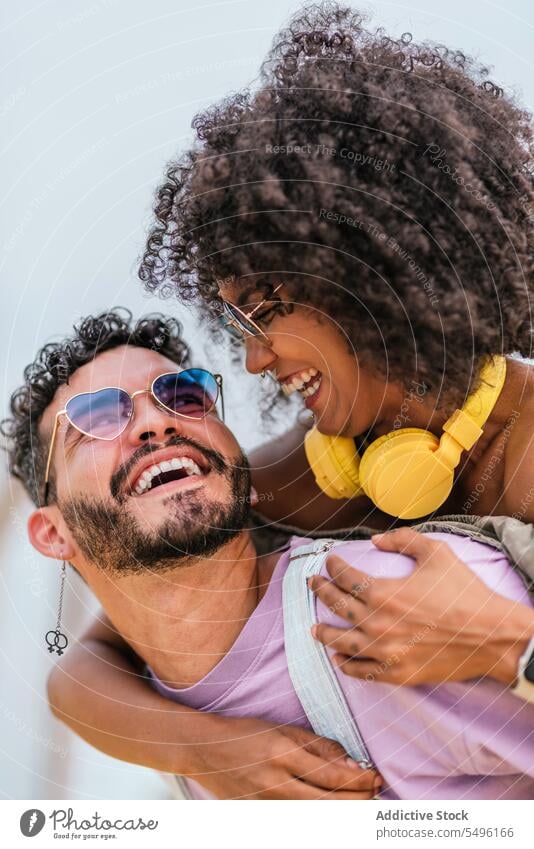 Cheerful young couple cuddling and looking at each other laugh happy embrace enjoy positive love cheerful headphones hipster hug sunglasses together
