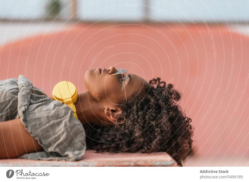 Woman lying on floor with yellow earphones woman rest relax smile happy chill alone positive calm content recreation modern glad enjoy healthy optimist using