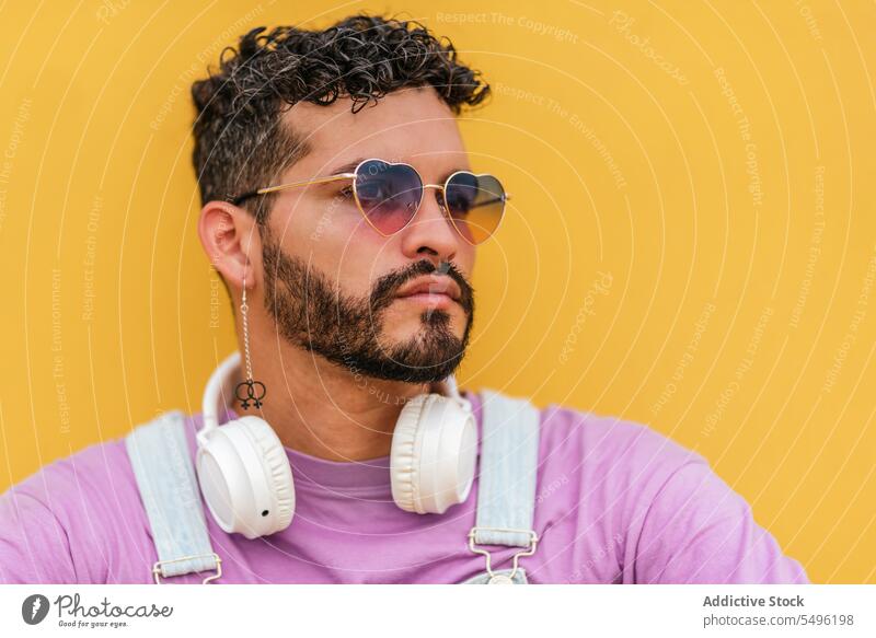 Bearded man with headphones and eyeglasses looking away against yellow background thoughtful serious dreamy portrait headset beard pensive eyewear using