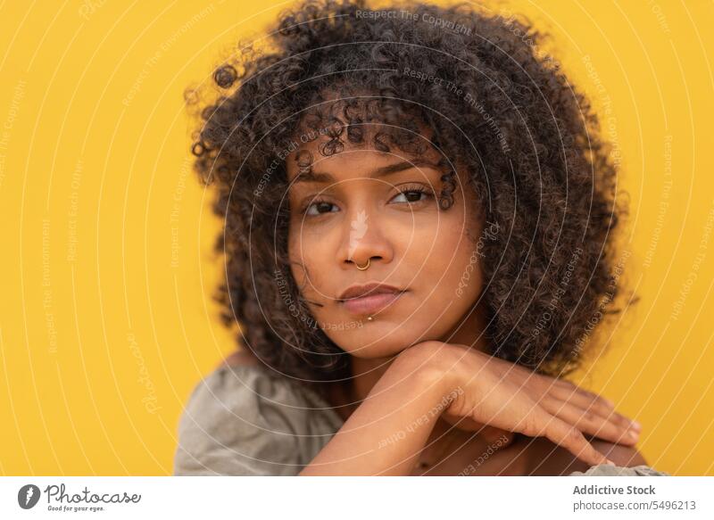 Dreamy young woman with curly hair think thoughtful piercing touch chin pensive serious human face model casual fashion accessory hand at chin dreamy look