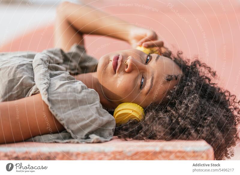 Woman lying on floor with yellow earphones woman rest relax smile happy chill alone positive calm content recreation modern glad enjoy healthy optimist using