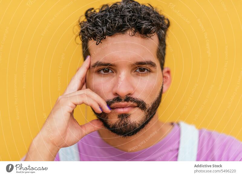 Young bearded man looking at camera against yellow background touch confident touch face positive sad upset stress displease human face mood alone worried