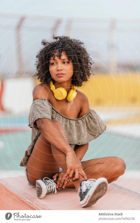 Curly haired female relaxing on bench woman thoughtful pensive serious think confident sit dreamy curly hair lifestyle elegant apparel african american beauty