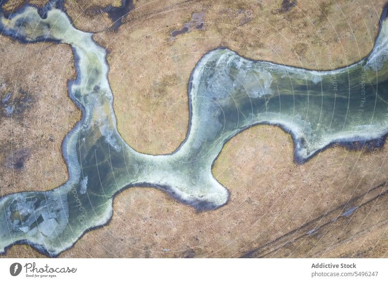 Drone view of meandering frozen river on sandy terrain in daylight landscape nature forest water scenery environment rough scenic picturesque spectacular