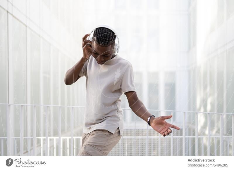 Black man in headphones dancing on street teenage music dance listen wireless move gadget urban positive young ethnic black african american device happy male