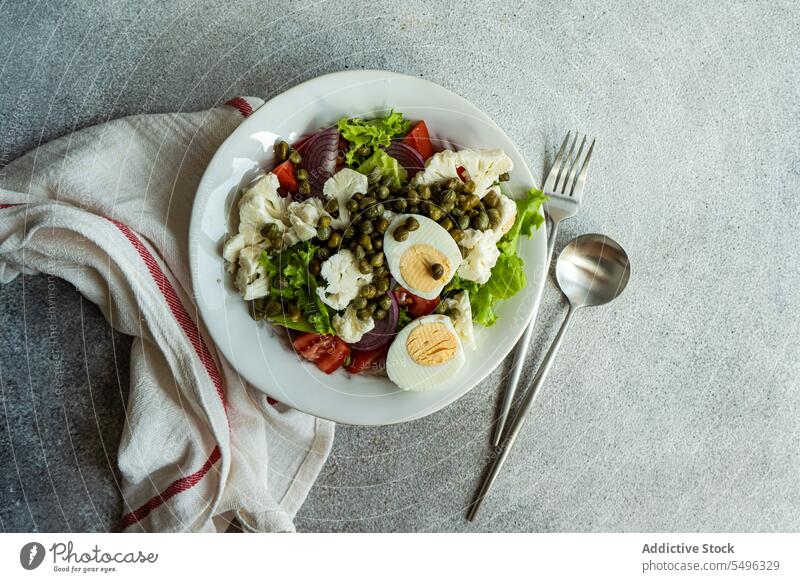 Keto salad with salad leaves, boiled eggs, capers, tomato, red onion and cauliflower vegetables. plate dish keto leaf green traditional recipe health healthy