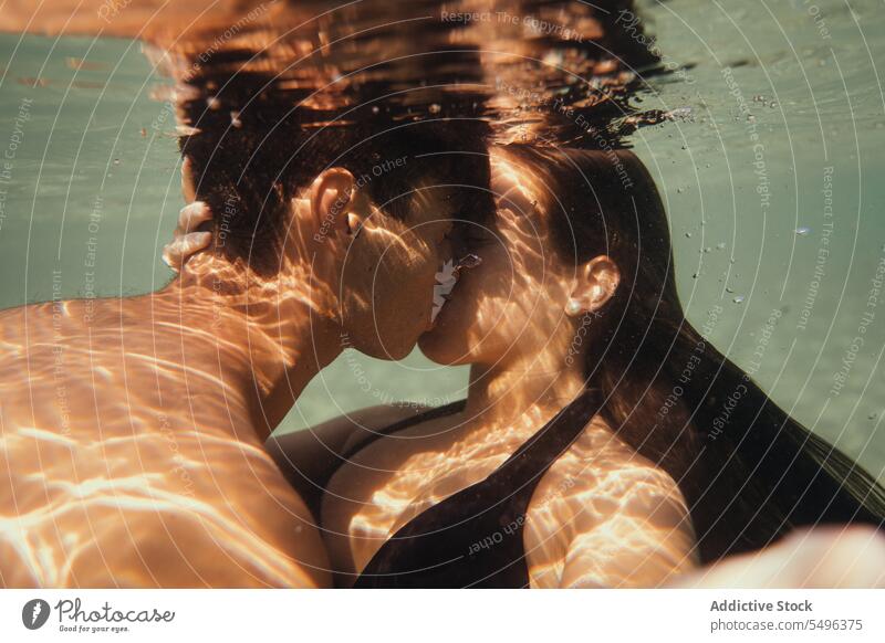 Young couple kissing under water man woman young male female love sea underwater side view crop brunette closed eyes romantic summer vacation holiday free time