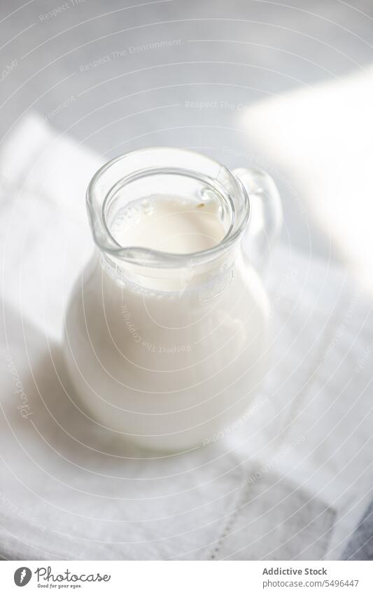 Raw milk in glass jar on white blurred napkin raw cow rustic drinking gray surface transparent fresh product beverage breakfast nutrition container nutritional