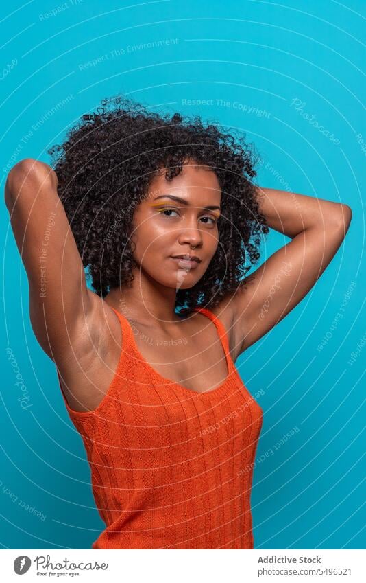 Slender black woman in orange top fashion model slim slender dark hair curly hair portrait female african american outfit cloth wear casual brunette afro