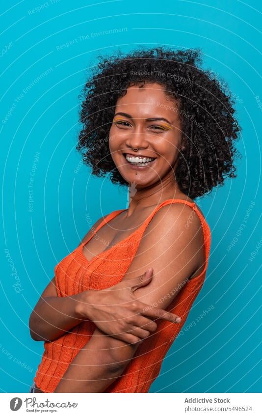Smiling black woman in orange top looking at camera fashion model slim dark hair curly hair female african american outfit cloth wear casual brunette afro
