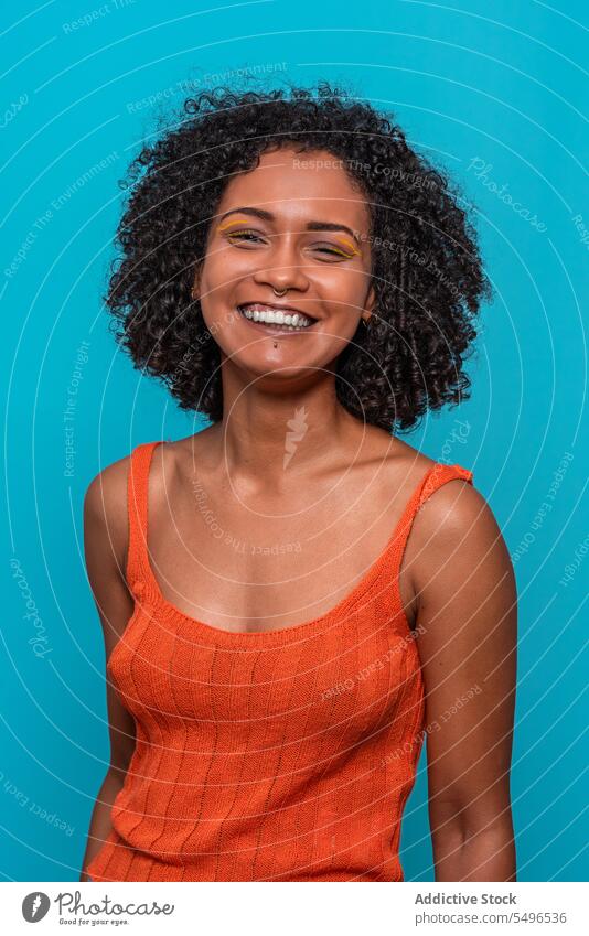 Smiling black woman in orange top looking at camera fashion model slim dark hair curly hair female african american outfit cloth wear casual brunette afro