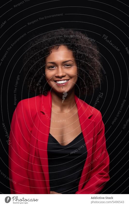 Smiling ethnic woman in red trendy outfit coat contemplate millennial model style confident afro appearance female young hairstyle curly hair individuality lady