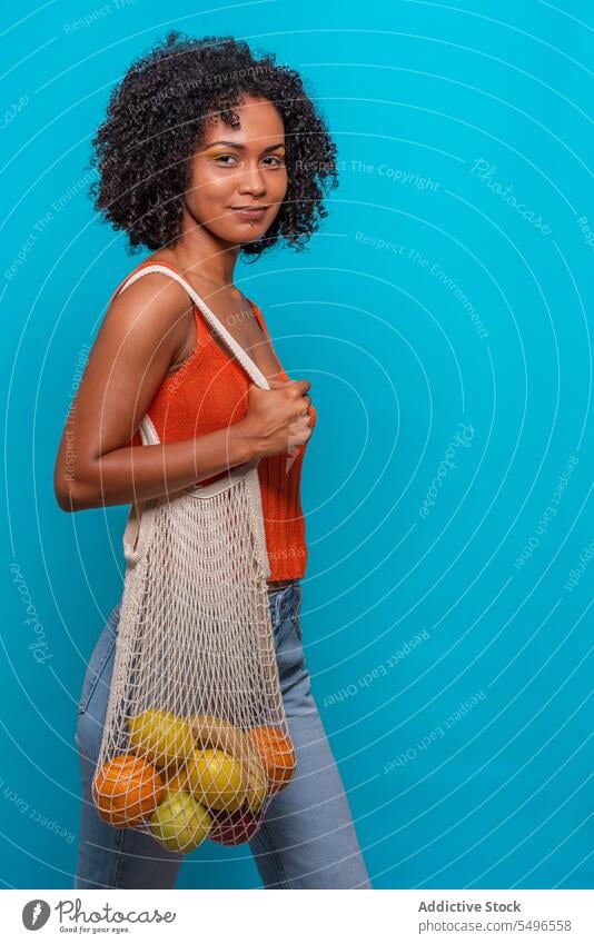 Happy black woman with fruit model afro hairstyle carry bag happy delight female african american casual outfit wear cloth top jeans denim slim curly hair